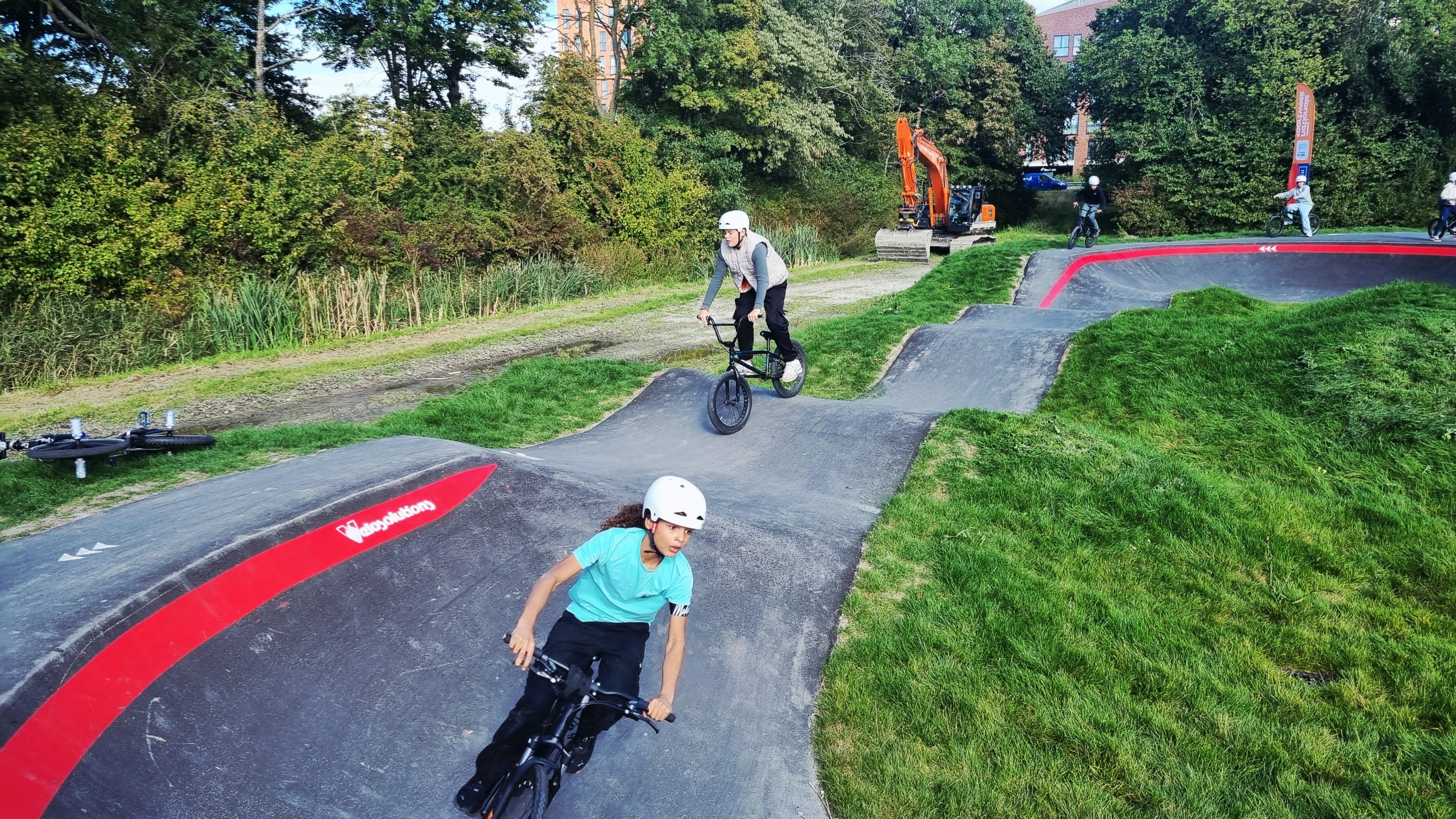 Foto: kinderen fietsen met een BMX over de nieuwe pumptrack.